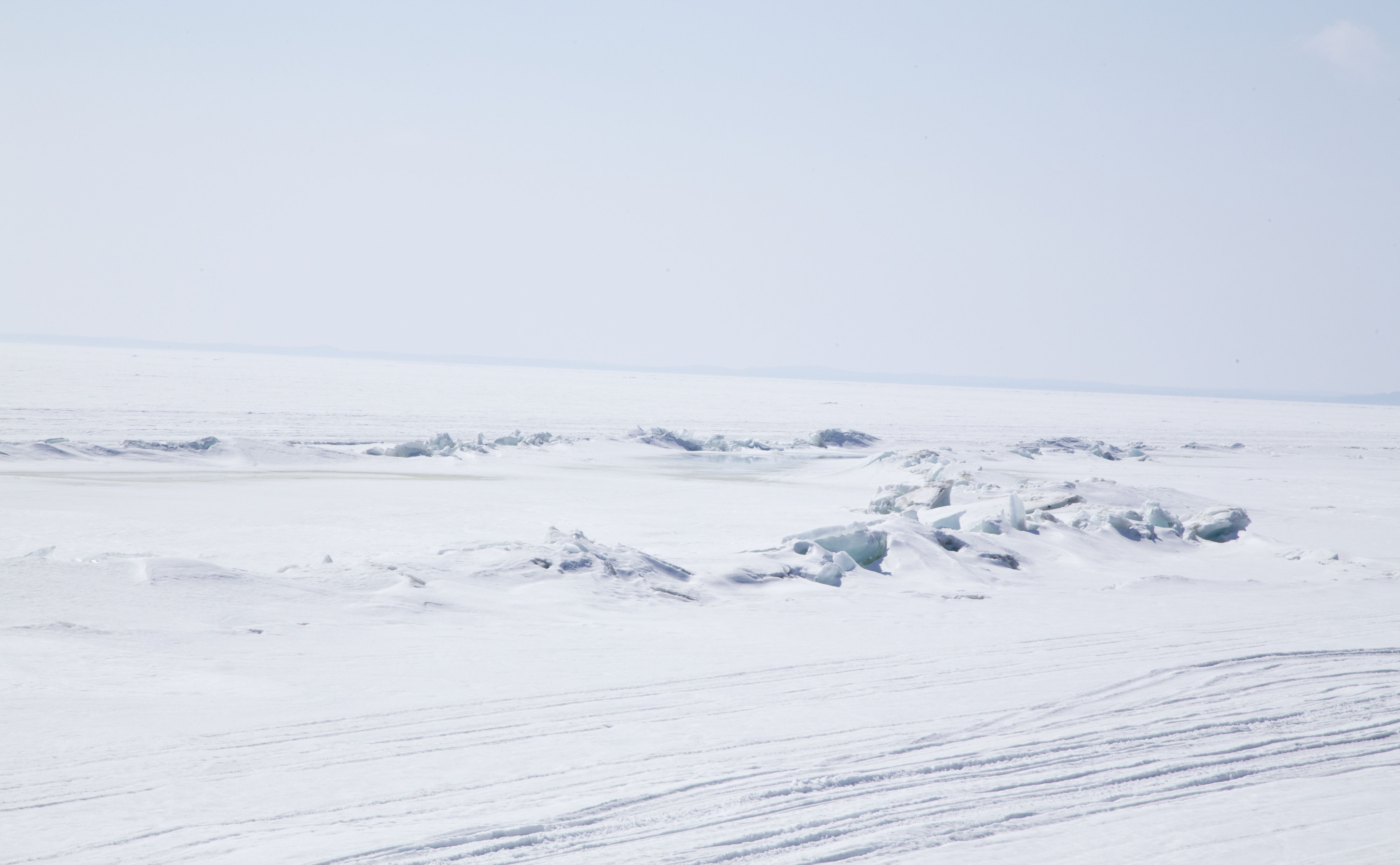 A frozen, snow-covered lake stretching to the horizon