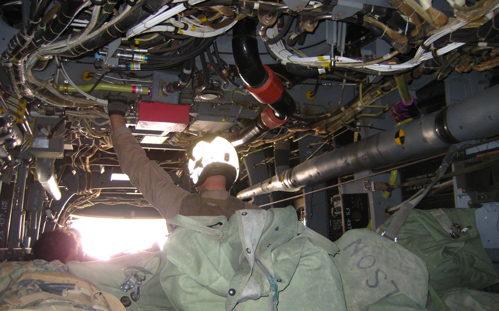 Wedged in the cramped cargo space of the aircraft, among overhead wiring and cargo bags